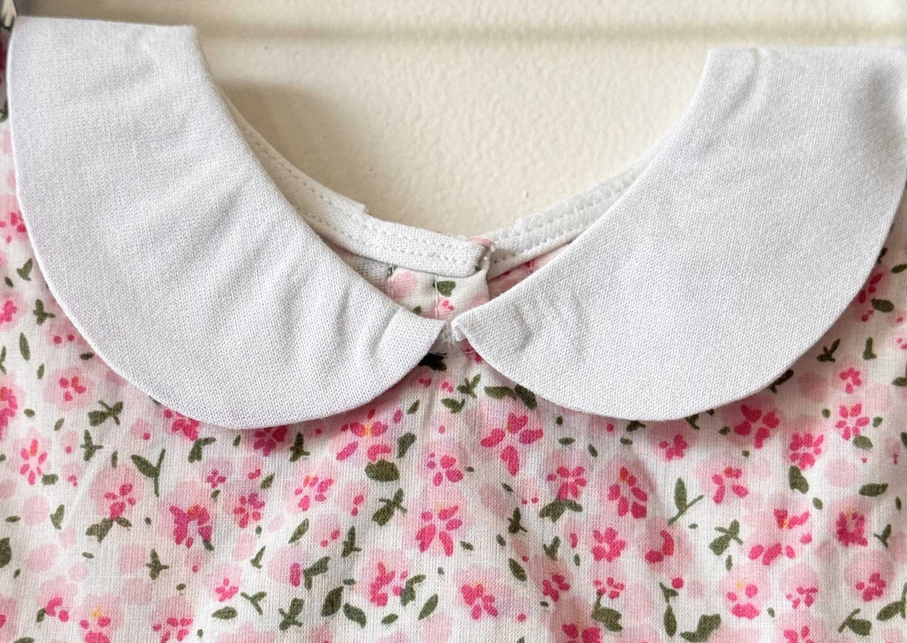 Close-up of a white Peter Pan collar on a pink floral print baby dress.