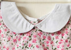 Close-up of a white Peter Pan collar on a pink floral print baby dress.