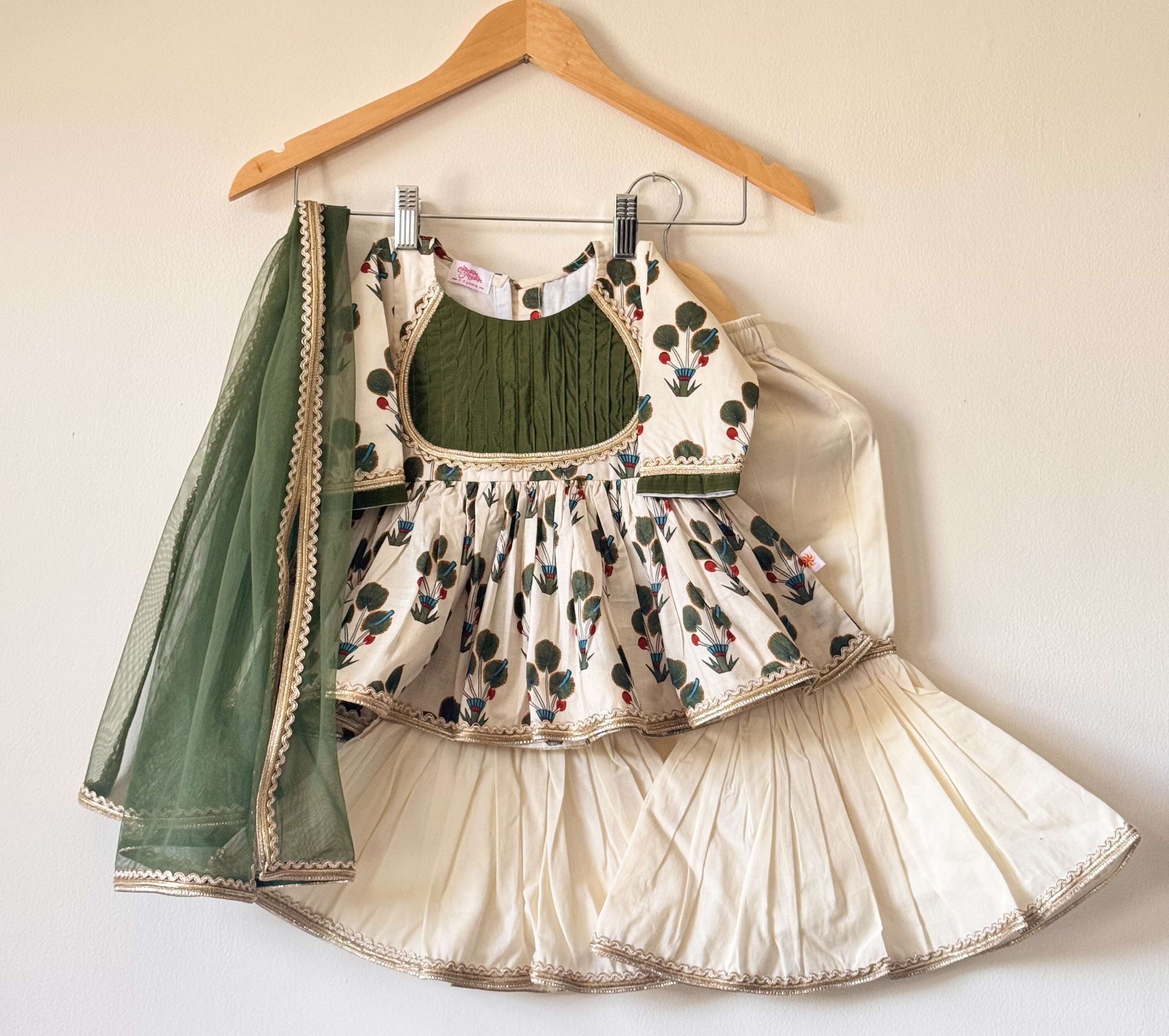 Girls' off-white and green floral cotton kurti and sharara set with a matching green net dupatta.