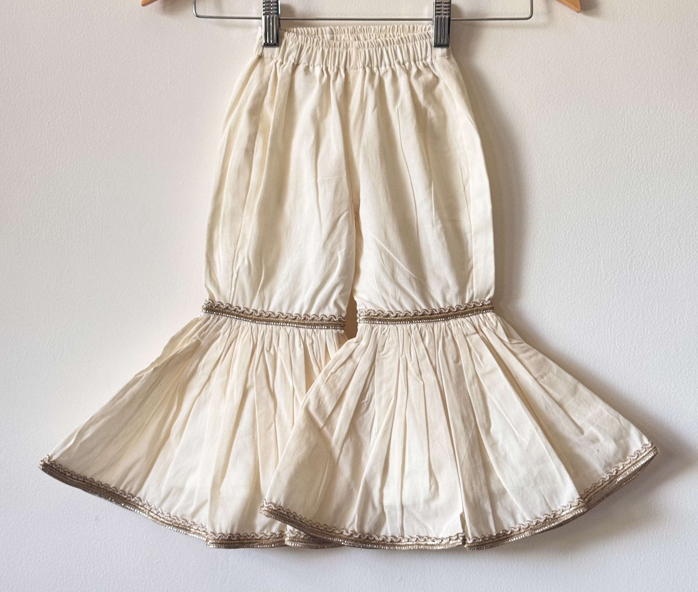 Girls' off-white tiered cotton sharara pants with gold lace detailing and an elastic waistband.
